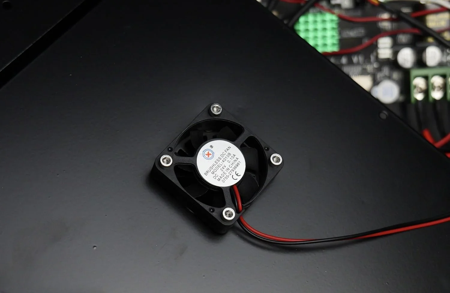 Qidi X Max internal fan, black with red and black wires, mounted on a metal plate, connected to circuit board, part of 3D printer components.