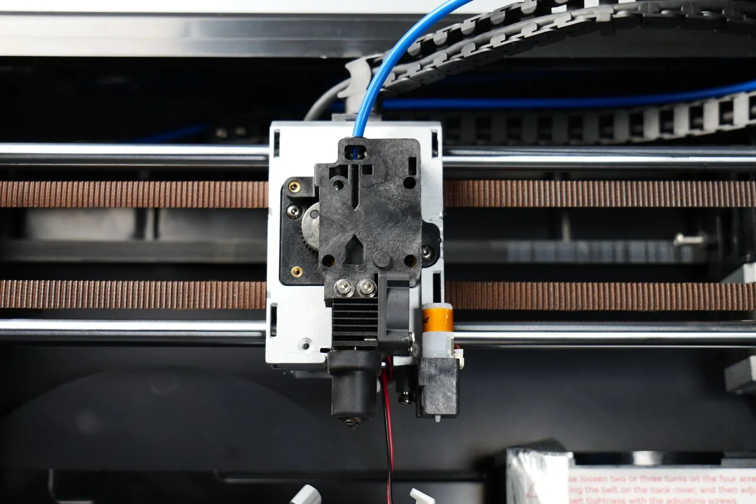 Qidi X-Max 3D printer interior, showing the print head assembly with wiring and belts, highlighting its technical construction details.