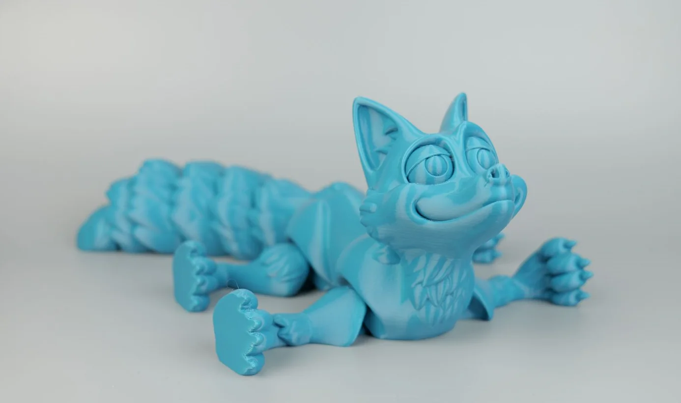 Blue 3D-printed fox figurine with articulated tail, created by Qidi X Max, displayed on a light background.