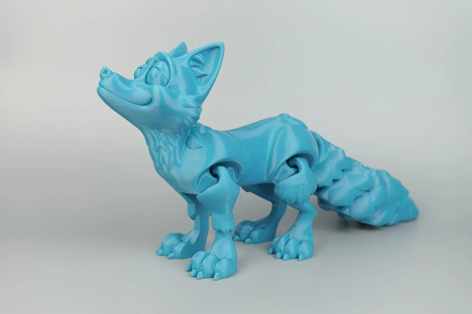 Blue articulated fox figurine 3D printed using Qidi X Max, demonstrating intricate details and mobility, on a neutral background.