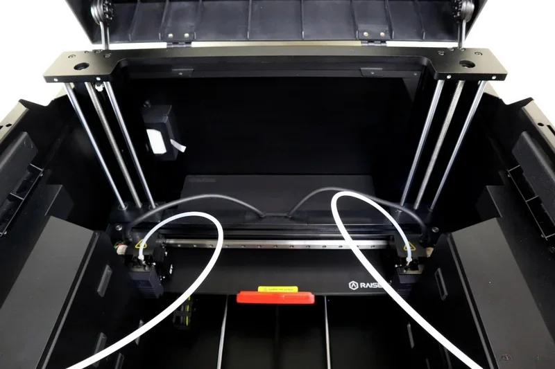 Raise3D E2 3D printer interior view showing dual extrusion system, filament tubes, and branding, designed for precise, high-quality part production.