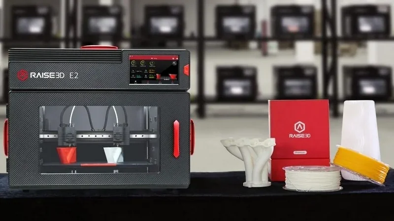 Raise3D E2 3D printer with dual extruders, touchscreen, samples, and branding on display in a professional setting.