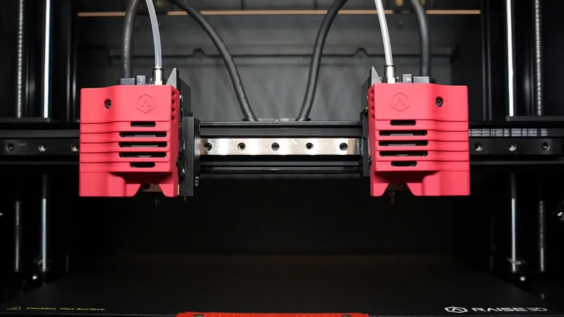 Raise3D E2CF 3D printer with dual red extruders, enclosed build chamber, and branding, specialized for creating complex parts with precision.