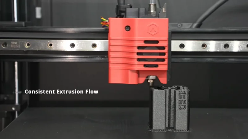 Raise3D E2CF 3D printer head extruding black part, showcasing consistent extrusion flow, visible branding, and print quality.