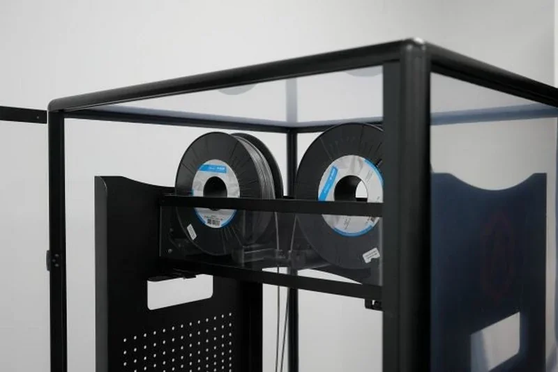 Raise3D MetalFuse printer with filament spools inside a transparent enclosure, designed for crafting precise metal parts.