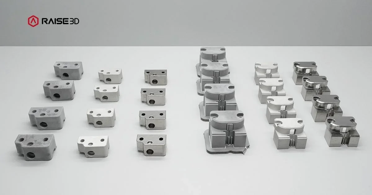 Raise3D MetalFuse 3D printed metal parts arranged neatly, showcasing precision and variety, with visible branding on the top left.