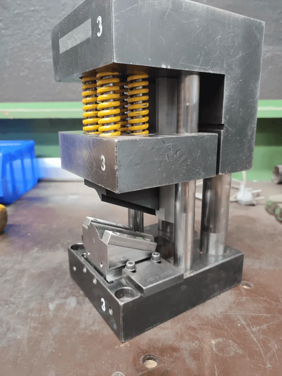 Industrial press with metal parts created by Raise3D MetalFuse. Features yellow springs and a sturdy metal base.