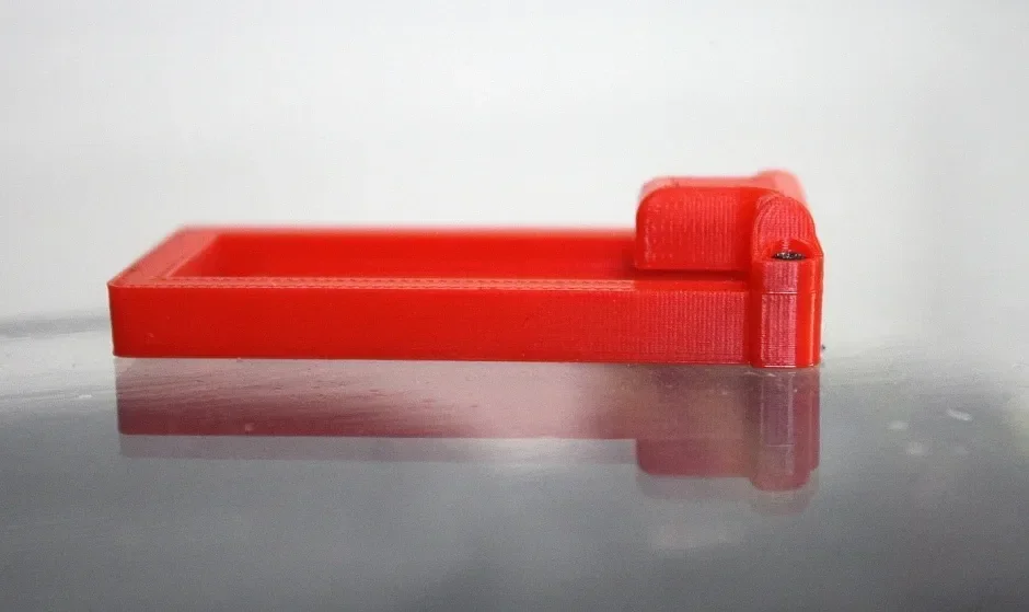 Red 3D-printed part on reflective surface, created by Raise3D Pro2 Plus, showcasing intricate detail and precise layering technology.