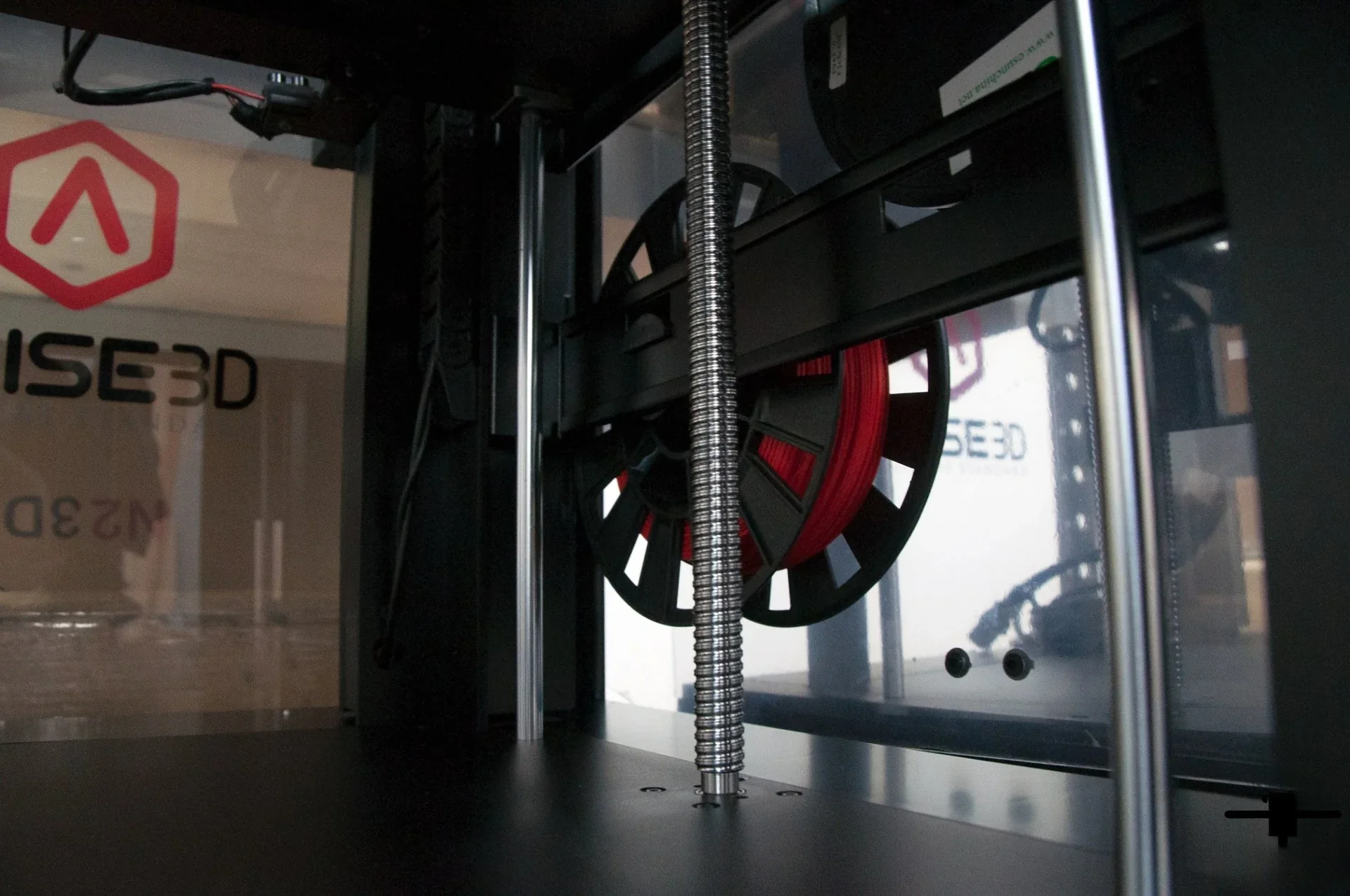 Raise3D Pro2 Plus interior showing filament spools with the Raise3D logo in the background, underlining advanced 3D printing capabilities.