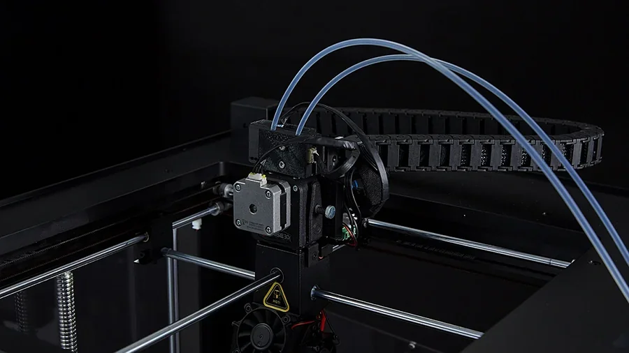 Raise3D Pro2 Plus 3D printer close-up showing the extruder and filament tubes, with a sleek design against a dark background.