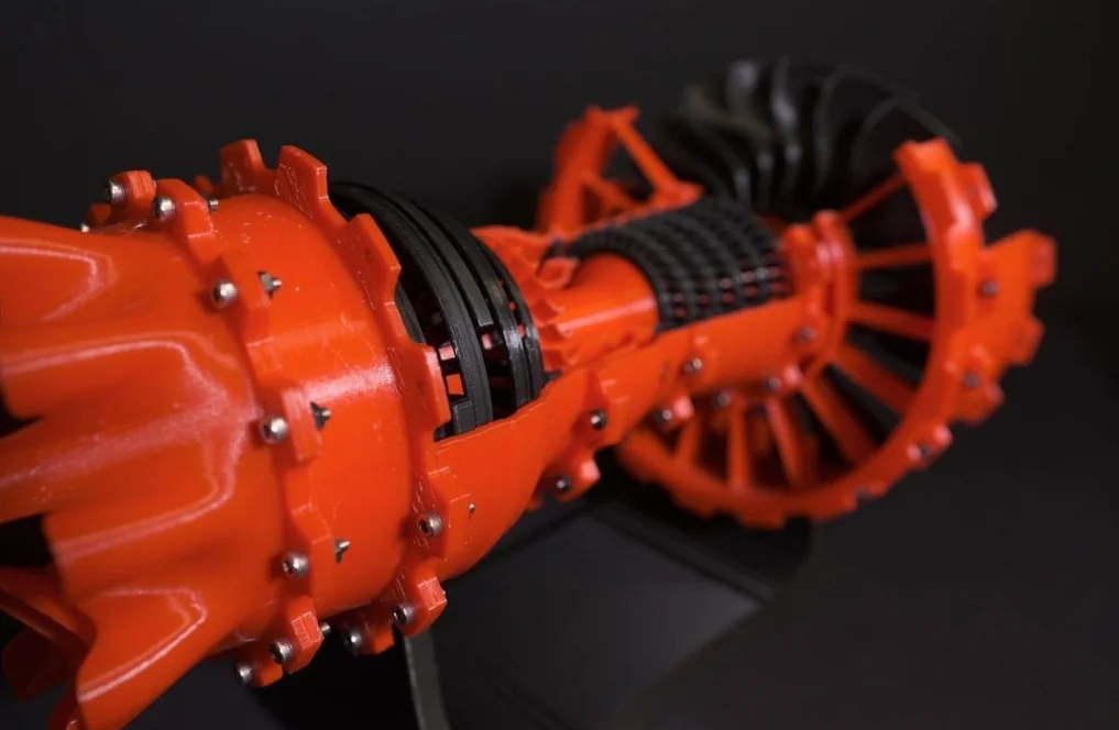 Red 3D-printed turbine model with detailed components, created by Raise3D Pro2 Plus, displayed against a dark background.