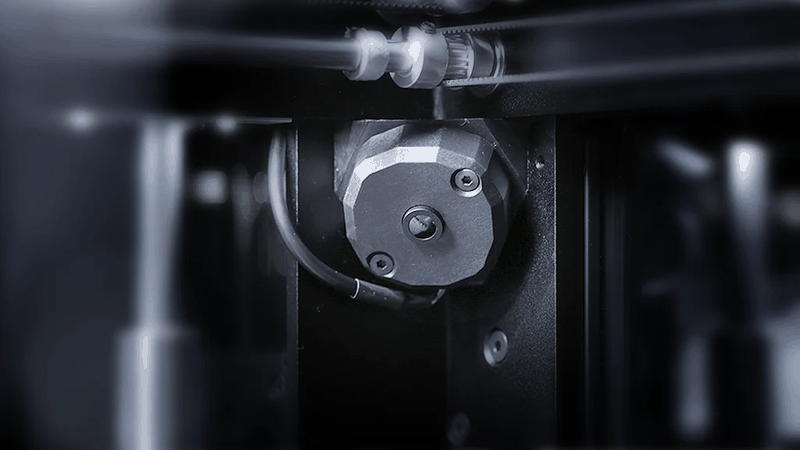 A close-up view of the Raise3D Pro3 HS printer’s extruder assembly. The image highlights intricate mechanical components, including a motor and wiring, demonstrating the precision engineering involved in the printer's material delivery system. The setting suggests a focus on the technology and craftsmanship of the Raise3D Pro3 HS.
