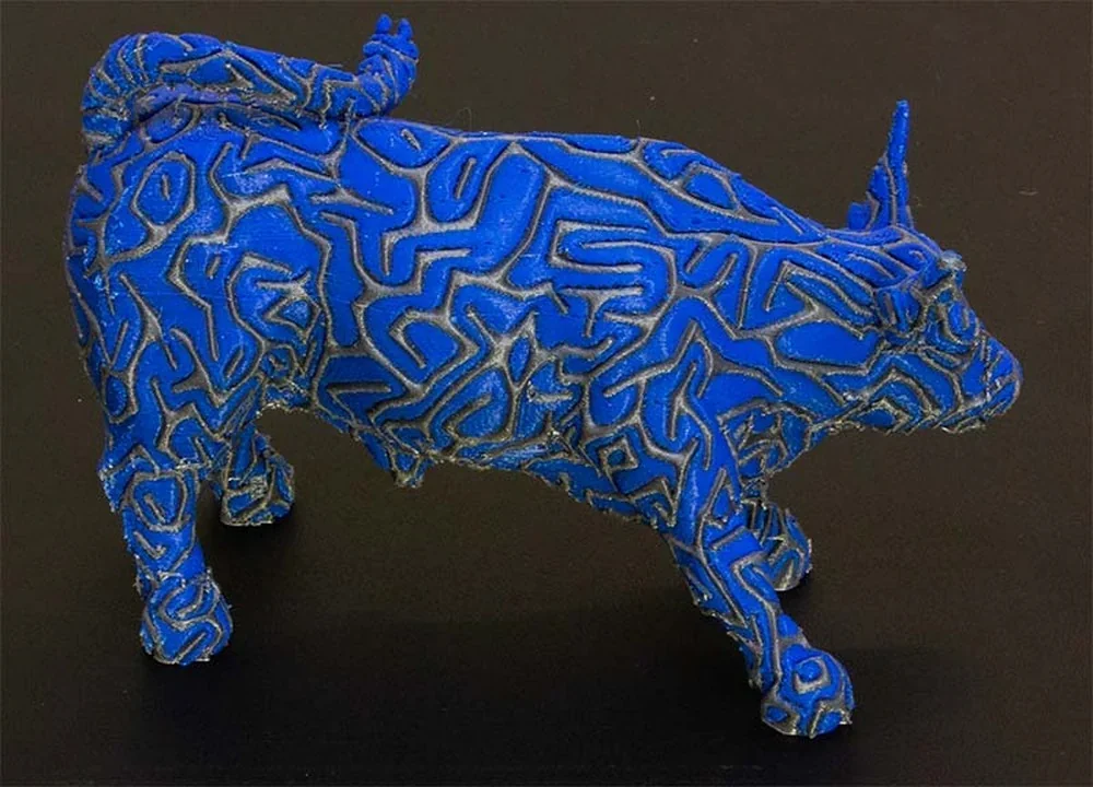 Blue 3D-printed bull with intricate patterns, created by Raise3D Pro3 Plus, on a dark surface, showcasing precise design and detailed craftsmanship.