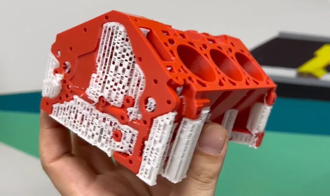 Red and white 3D-printed engine model held in hand, created by Raise3D Pro3 Plus, showcasing intricate design and print detail.