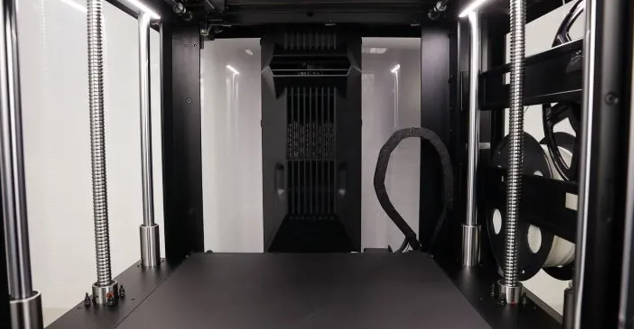 Raise3D Pro3 Plus HS 3D printer interior with linear rods, filament spools, and a black build plate, showcasing precision engineering.