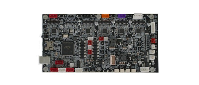 A detailed view of the main control board for the Raise3D Pro3 Plus HS 3D printer. The board features numerous components, including a prominent Atmel microcontroller, several connectors, and multiple inputs and outputs for interfacing with various printer parts. The array of capacitors, resistors, and other electronic components are arranged compactly, highlighting the complexity of the printer's control systems.