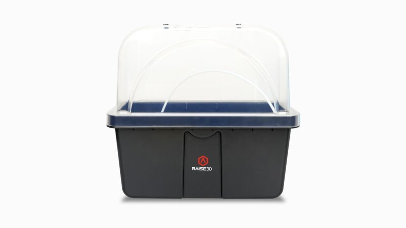 The image depicts a black, rectangular enclosure with a transparent dome lid branded "RAISE3D." It features a minimalistic design suitable for protecting 3D printer components, potentially belonging to the Raise3D Pro3 Plus HS series. The logo is centered on the front, offering a clean visual of the brand.