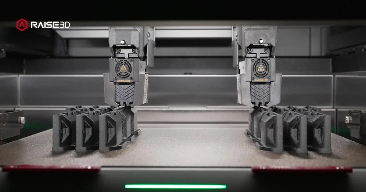 Raise3D RMF500 printing multiple black parts, showcasing industrial dual extruders with branding visible, in a sleek, modern setting.