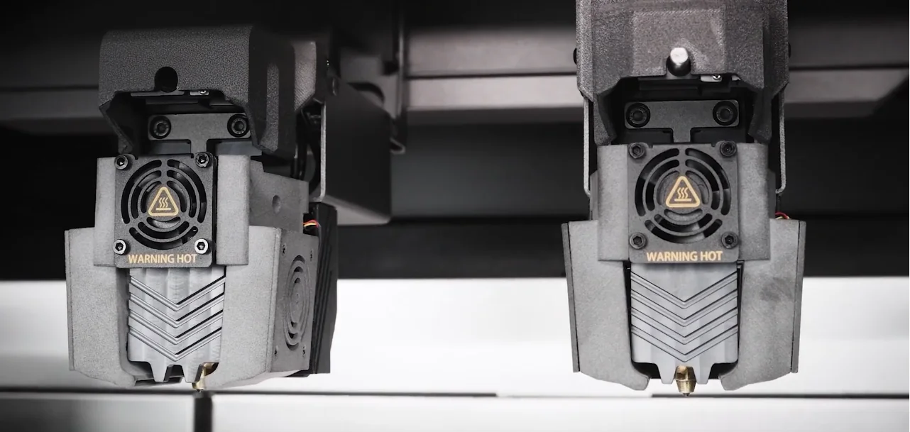 Raise3D RMF500 dual extruders with "Warning Hot" signs, highlighting advanced 3D printing technology and precision in manufacturing components.