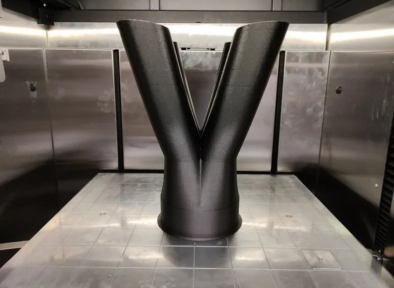 Industrial 3D-printed black Y-shaped object inside the Raise3D RMF500 printer, showcasing its large-scale manufacturing capability.