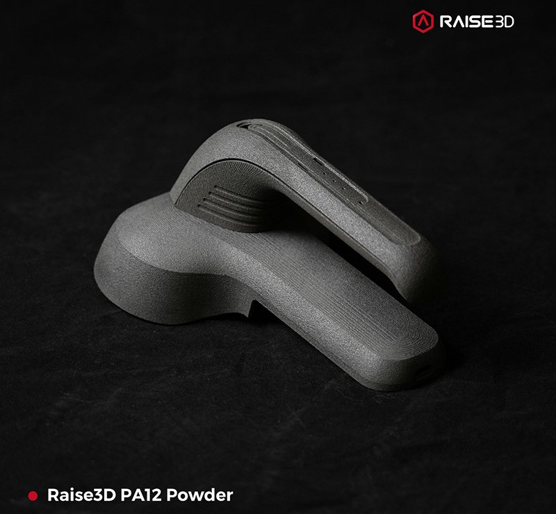 A gray 3D-printed part created using Raise3D PA12 Powder by the raise3d rms220 is displayed against a dark background. The complex, smooth design features multiple curves and ridges, indicating precision in printing. The branding "Raise3D" is visible at the top right corner with the product details in the bottom left, showcasing material capability and quality of the raise3d rms220 printing process.