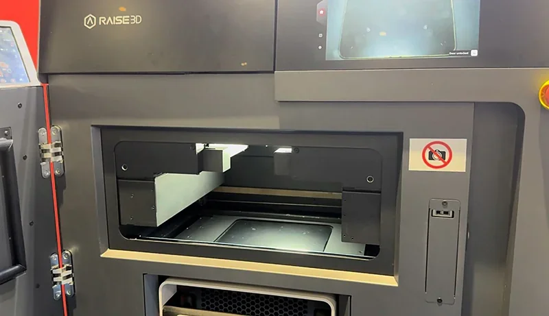 Raise3D RMS220 3D printer front view with open chamber, Raise3D branding, display screen, no smoking sign, showcasing printing space.