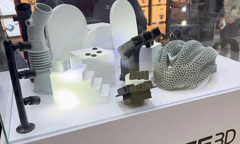 Raise3D RMS220 3D-printed parts including ducts and lattice structures displayed in a showcase, highlighting intricate and varied designs.
