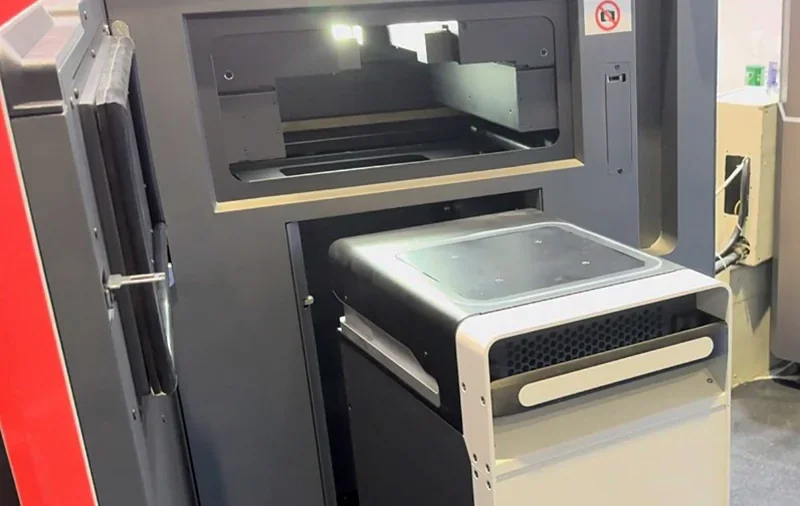 Raise3D RMS220 3D printer open, displaying internal build area; gray and black design, industrial setting.