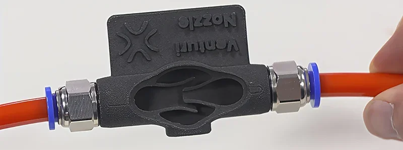 3D printed black Venturi nozzle, produced by Sinterit Lisa X, connected to red tubing with metal fittings, displaying internal structure.