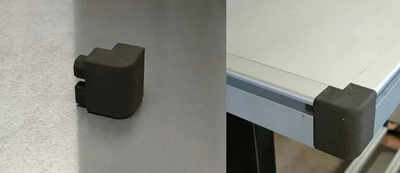 Sinterit Lisa X created corner bracket on a table edge, showcasing precise 3D printing capability, black material contrasts with metal table surface.
