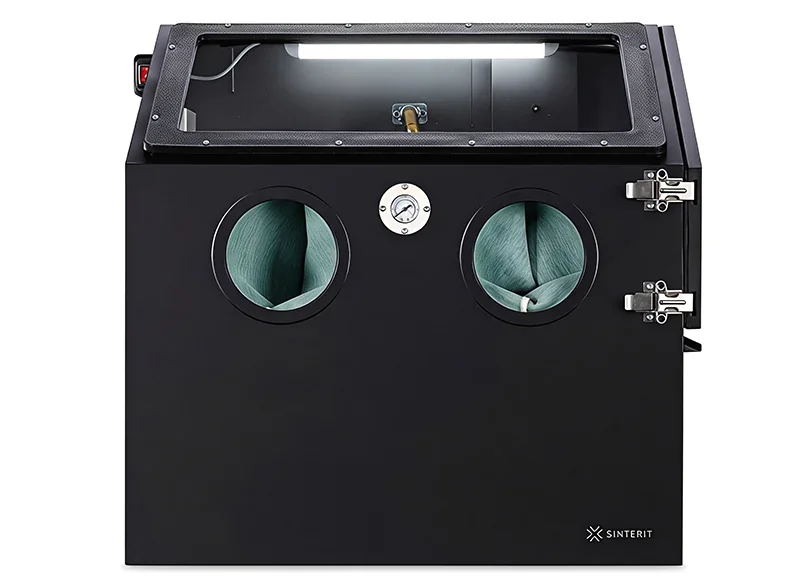Sinterit Lisa X 3D printer with dual glove ports and pressure gauge in a black enclosure, showcasing branding on the front panel.