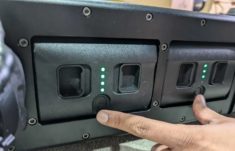 Finger pressing button on a Unitree H1 interface panel with lit green LED indicators, likely controlling robotic functions or settings.